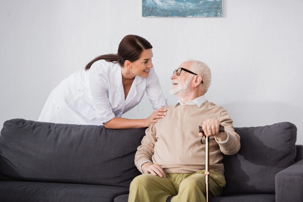 nurse helping elderly man on a coach